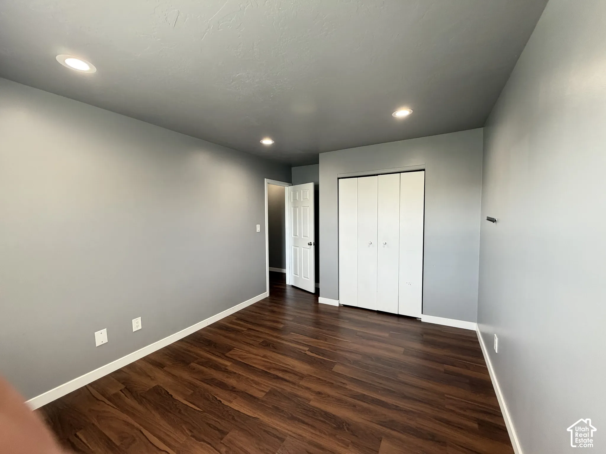 Room featuring wood-finish flooring, recessed lighting, and a multi-panel closet with white doors
