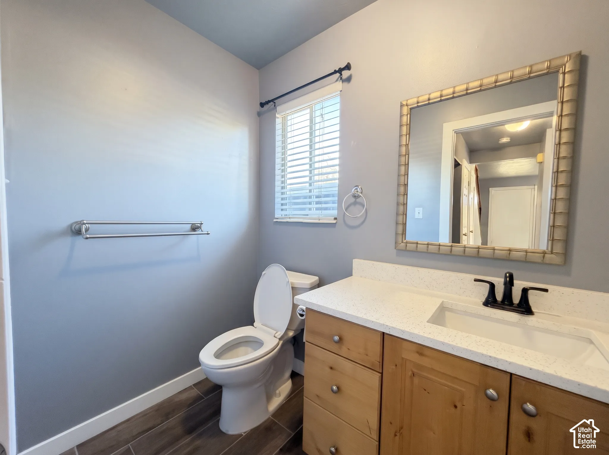 Bathroom featuring a vanity with wood-finish cabinetry, speckled solid-surface countertop, integrated rectangular sink, and matte black widespread faucet