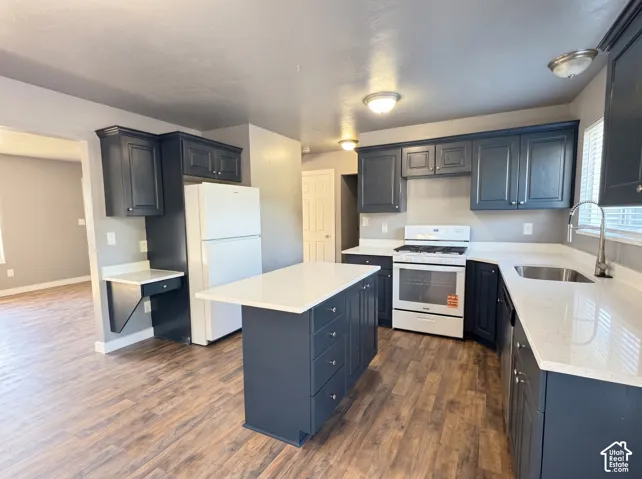 Kitchen featuring dark cabinetry, white countertops, a central island with drawer storage, and wood-finish flooring