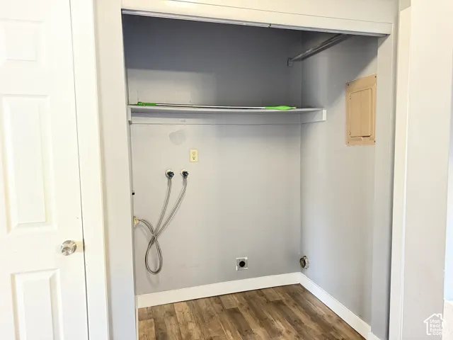 Utility alcove featuring wood-finish flooring, a built-in overhead storage shelf, a dedicated clothing rod, and water hookups