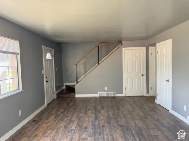 Interior space featuring wood-finish flooring, staircase with a wood handrail and cable railing, and three six-panel interior doors