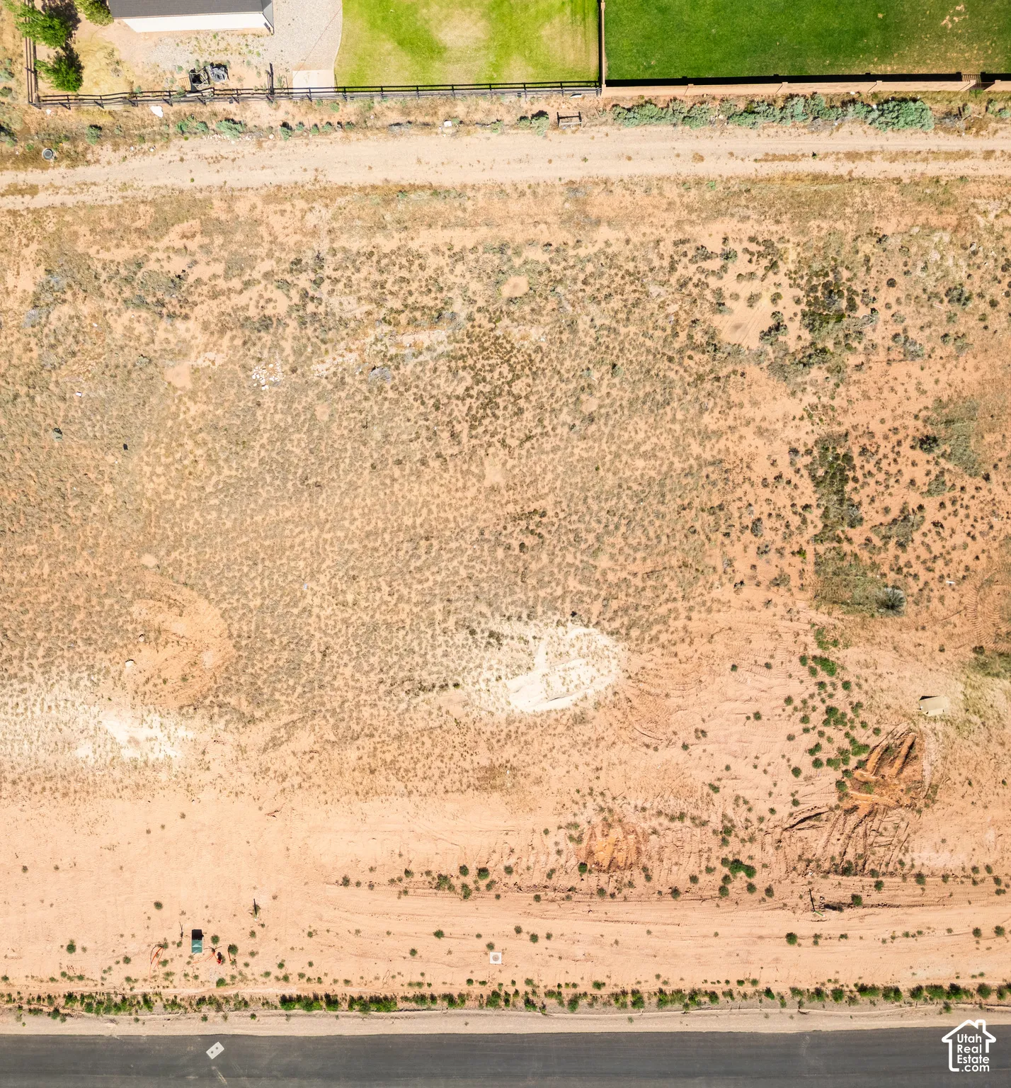 Expansive rectangular parcel featuring direct paved road access, perimeter fencing, and native desert terrain