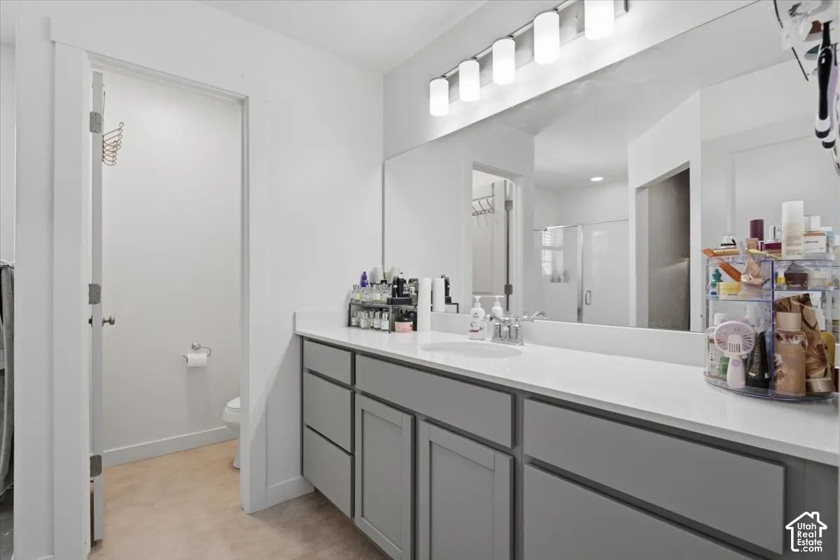 Bathroom vanity featuring grey shaker-style cabinetry, a white countertop, an oval undermount sink, a full-width wall mirror, and a five-light fixture