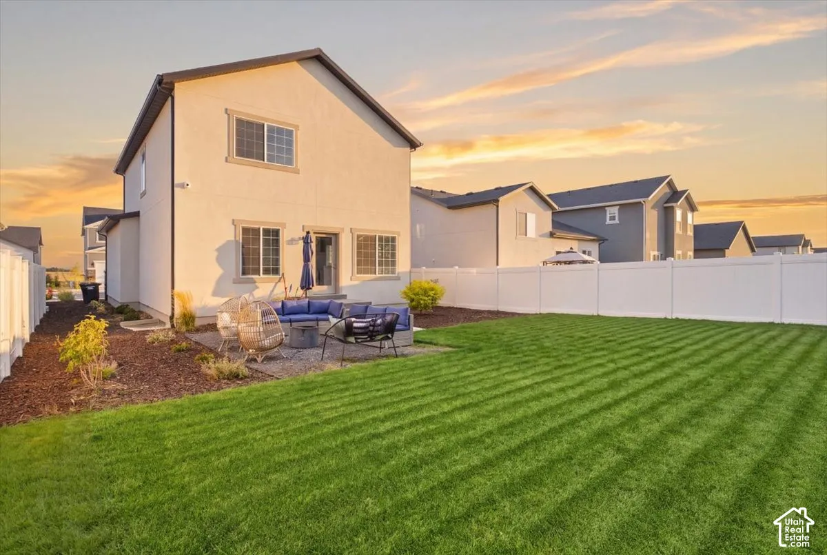 Backyard featuring a paved stone patio, manicured lawn, and vinyl privacy fencing