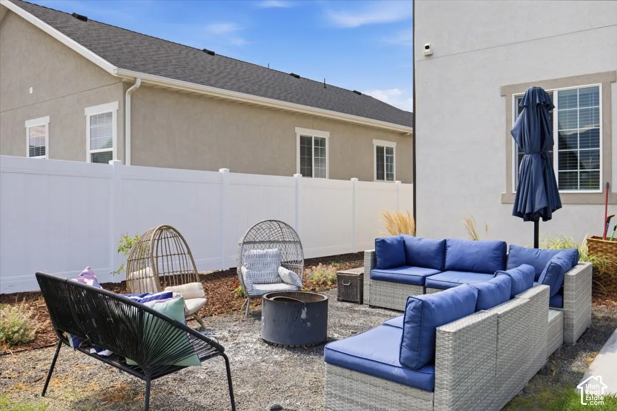Rear exterior space featuring a gravel patio, cylindrical metal fire pit, and a tall white vinyl privacy fence