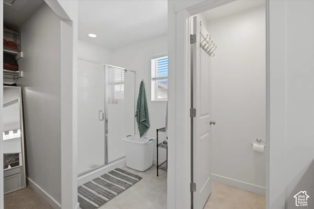 Bathroom featuring a walk-in shower with glass enclosure, recessed lighting, and tile-finish flooring
