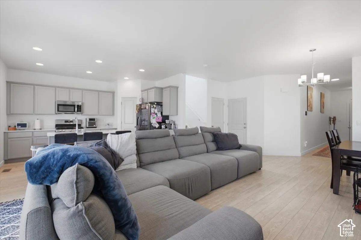 Open-concept kitchen featuring shaker-style cabinetry, wood-finish flooring, recessed lighting, and a multi-light chandelier