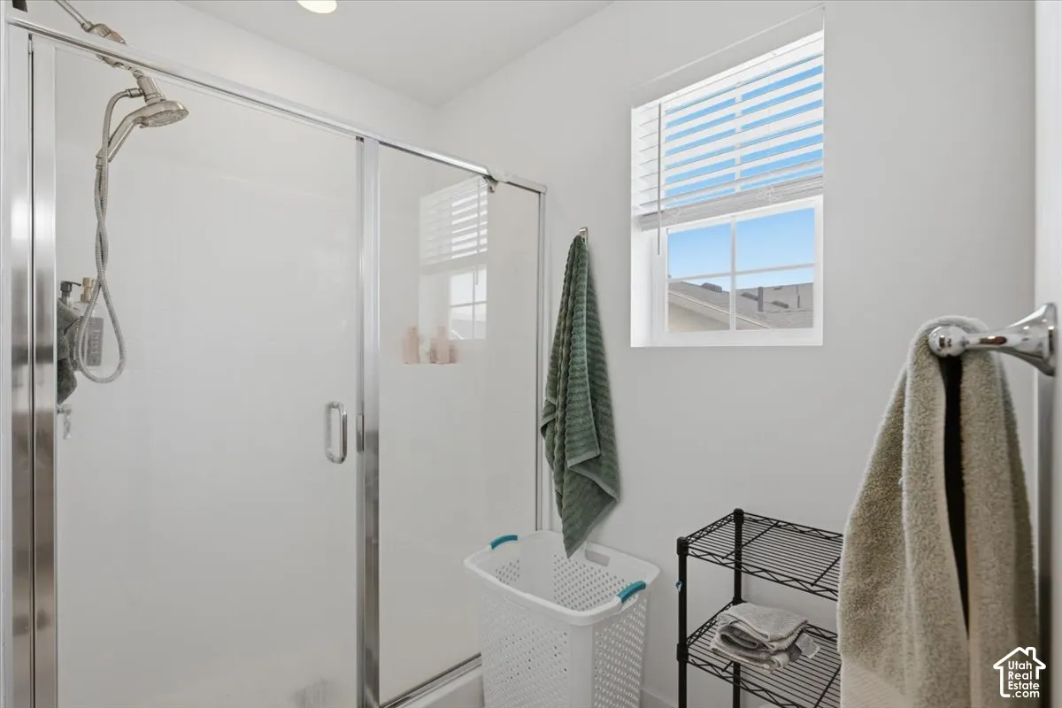 Walk-in shower with a chrome finish handheld fixture and glass enclosure, complemented by a horizontal window
