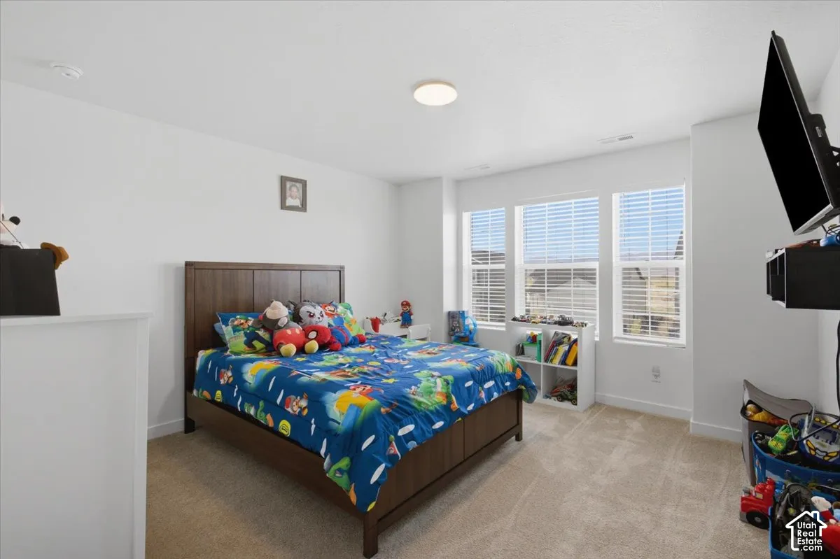 Neutral-toned room featuring neutral carpeting, a trio of windows with horizontal blinds, and a flush-mount ceiling light fixture