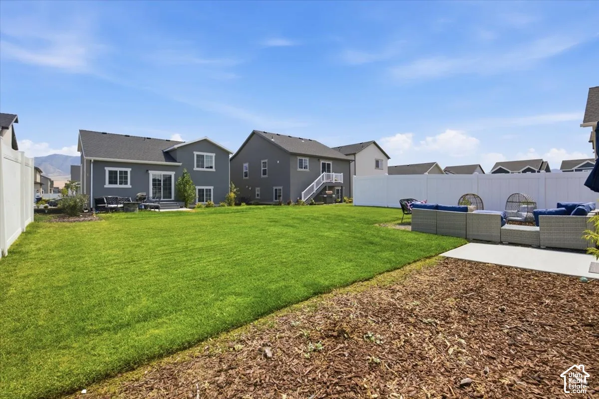 Spacious backyard featuring a manicured lawn, white vinyl perimeter fencing, and concrete patio areas