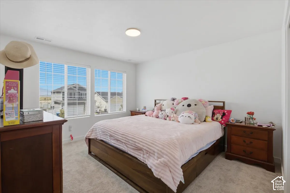 Neutral-toned interior space featuring light carpeting, crisp white walls, and triple-pane windows with horizontal blinds