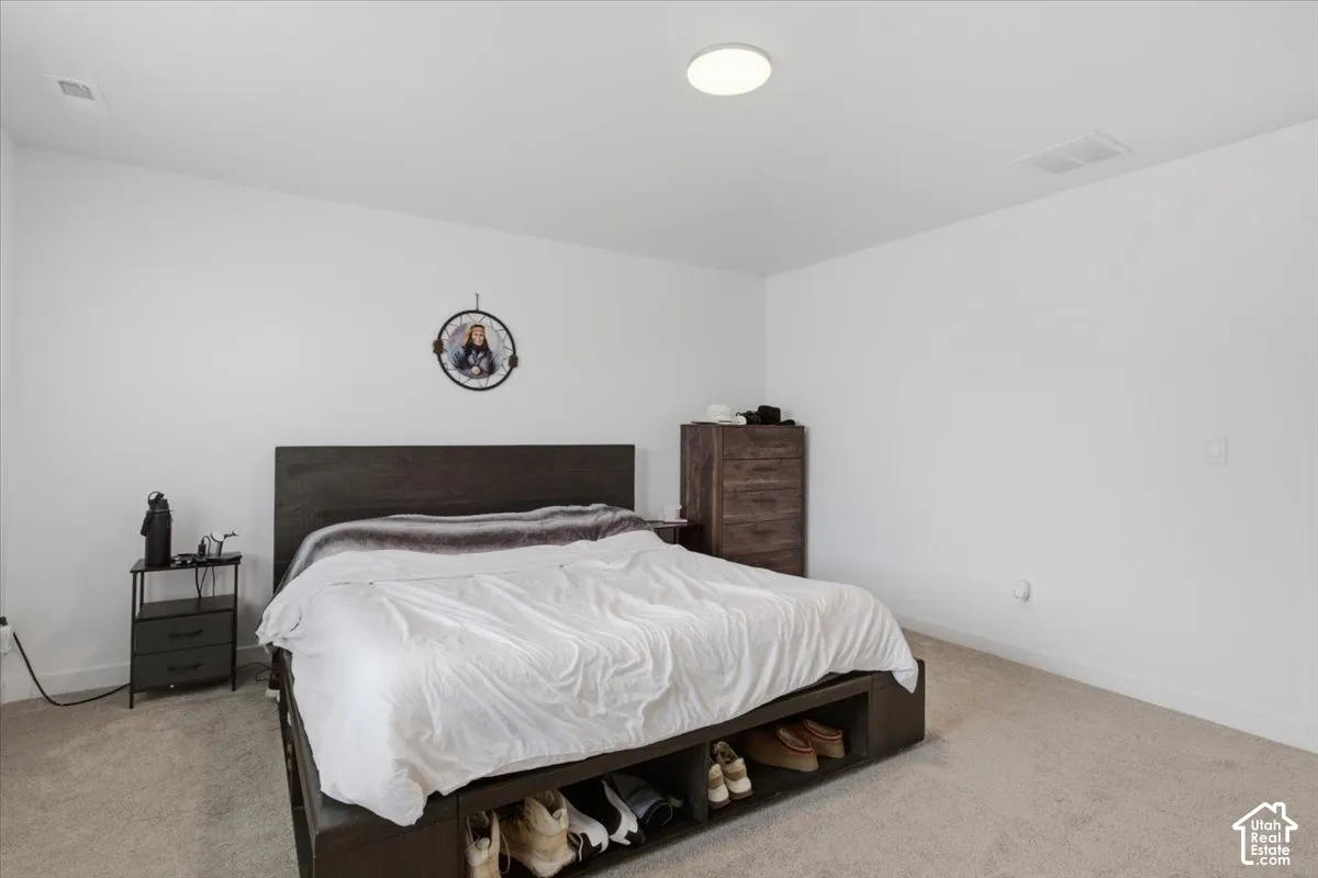 Neutral-toned interior space featuring light-colored wall-to-wall carpeting, crisp white wall finishes, and a flush-mount circular ceiling light
