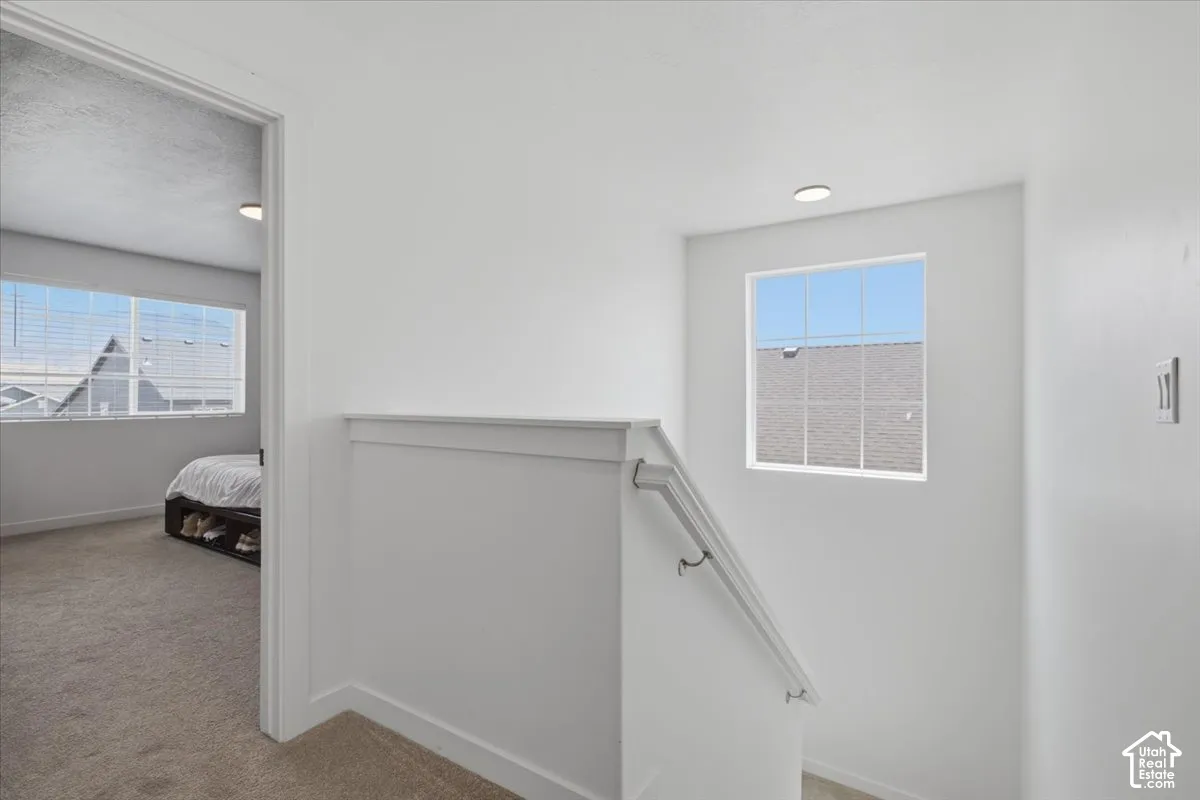 Landing featuring neutral wall-to-wall carpeting, recessed ceiling lighting, and a staircase with a white painted handrail