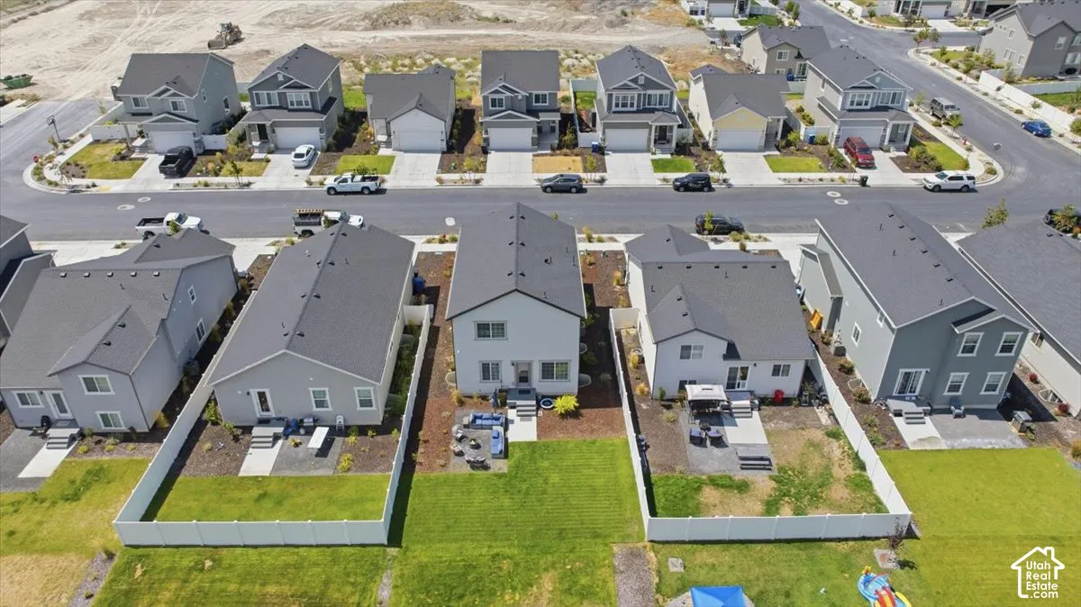 Aerial perspective of residential properties featuring fenced-in backyards, concrete patios, and manicured lawns