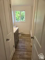 Bathroom featuring wood-finish tile flooring, a gray vanity cabinet with a white countertop, and a sliding window