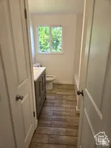 Bathroom featuring wood-finish flooring, a vanity with a solid-surface countertop, and a sliding window