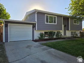 Split-level exterior featuring horizontal siding, white painted brick lower level, single-car garage, and concrete driveway