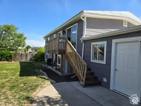 Exterior featuring horizontal siding, a raised wooden deck with staircase, concrete patio, and a fenced backyard