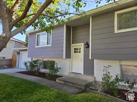 Exterior facade featuring horizontal siding and painted brick masonry, white-trimmed multi-pane entry door, attached single-car garage, and concrete walkway