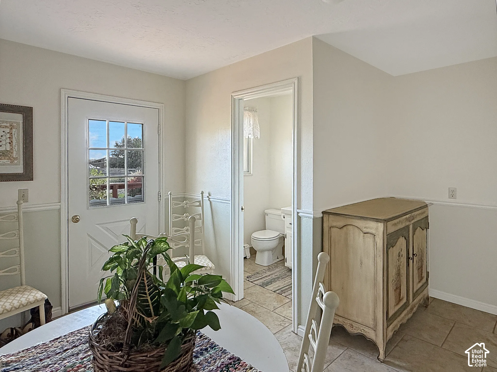 Neutral-tone interior space featuring two-toned wall finishes with chair rail molding, tile flooring, and a half-light door with a multipane window