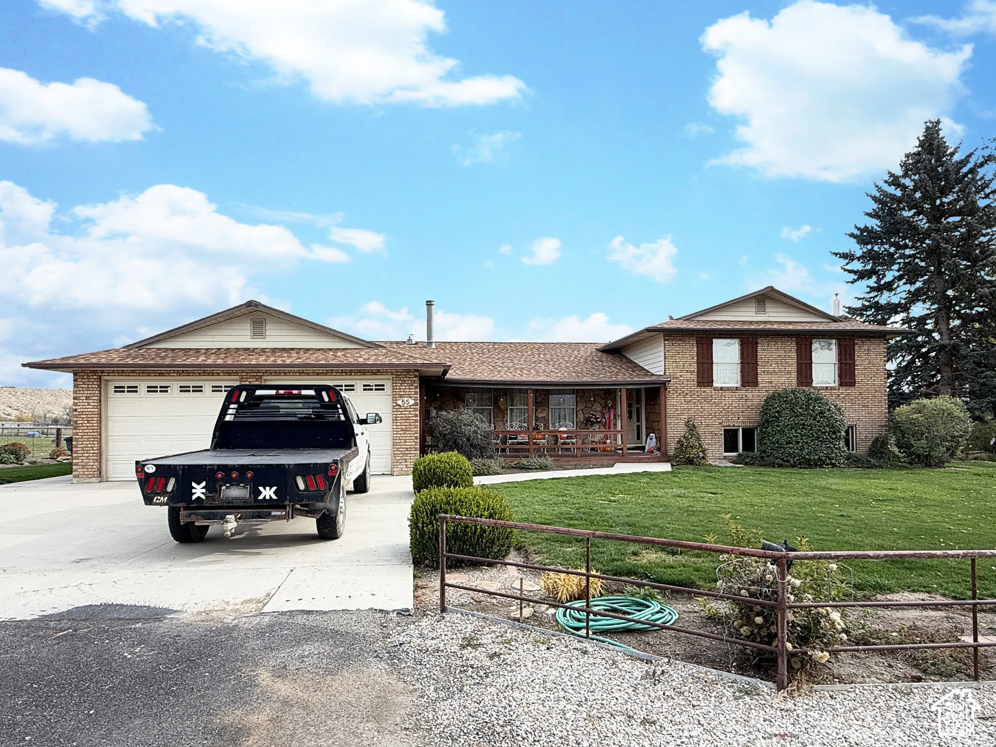 Split-level brick exterior featuring a multi-car garage, covered porch, and expansive front lawn