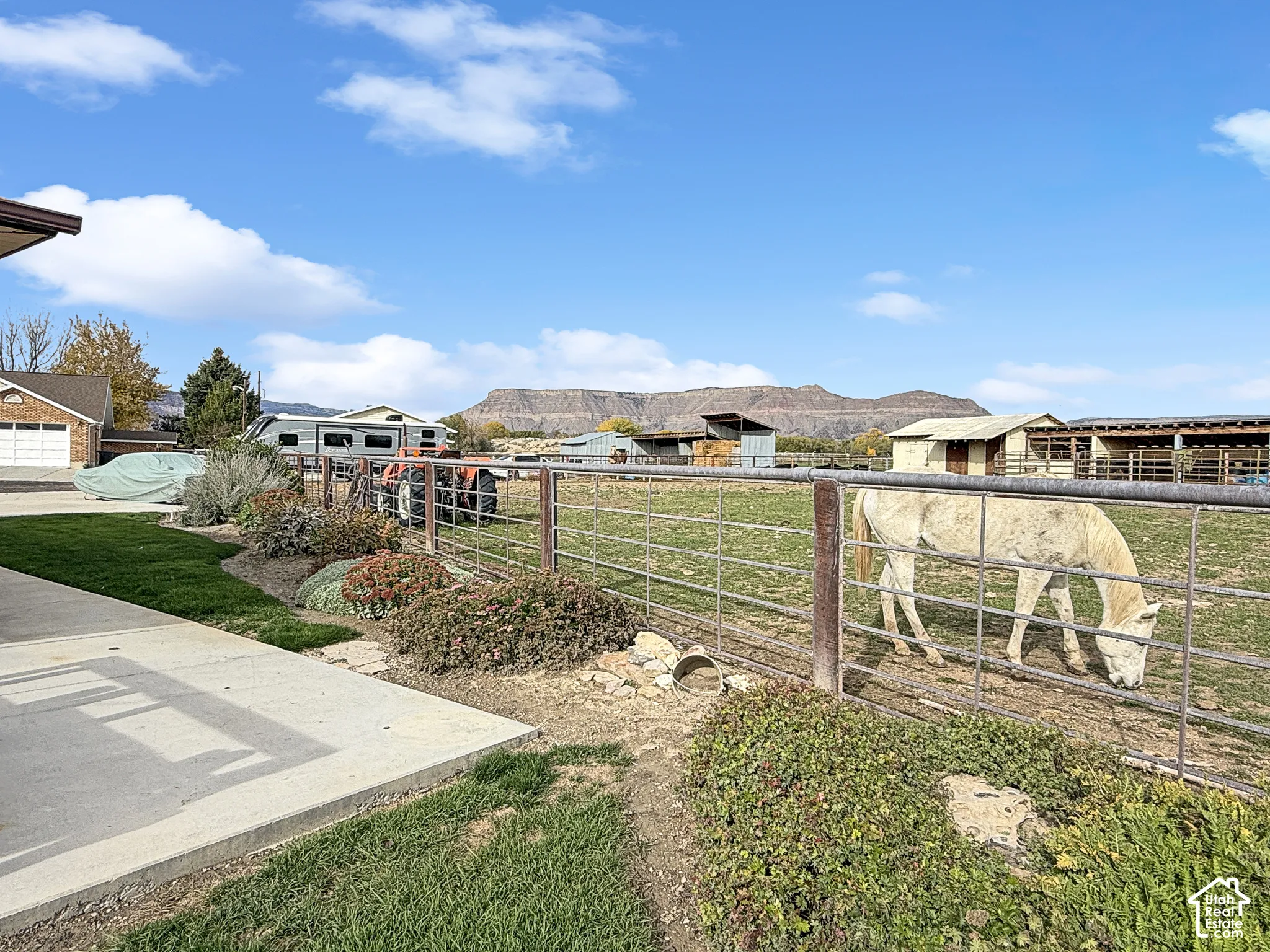 Expansive outdoor area featuring metal pipe fencing, manicured lawn, low-maintenance landscaping, and prominent mountain backdrop