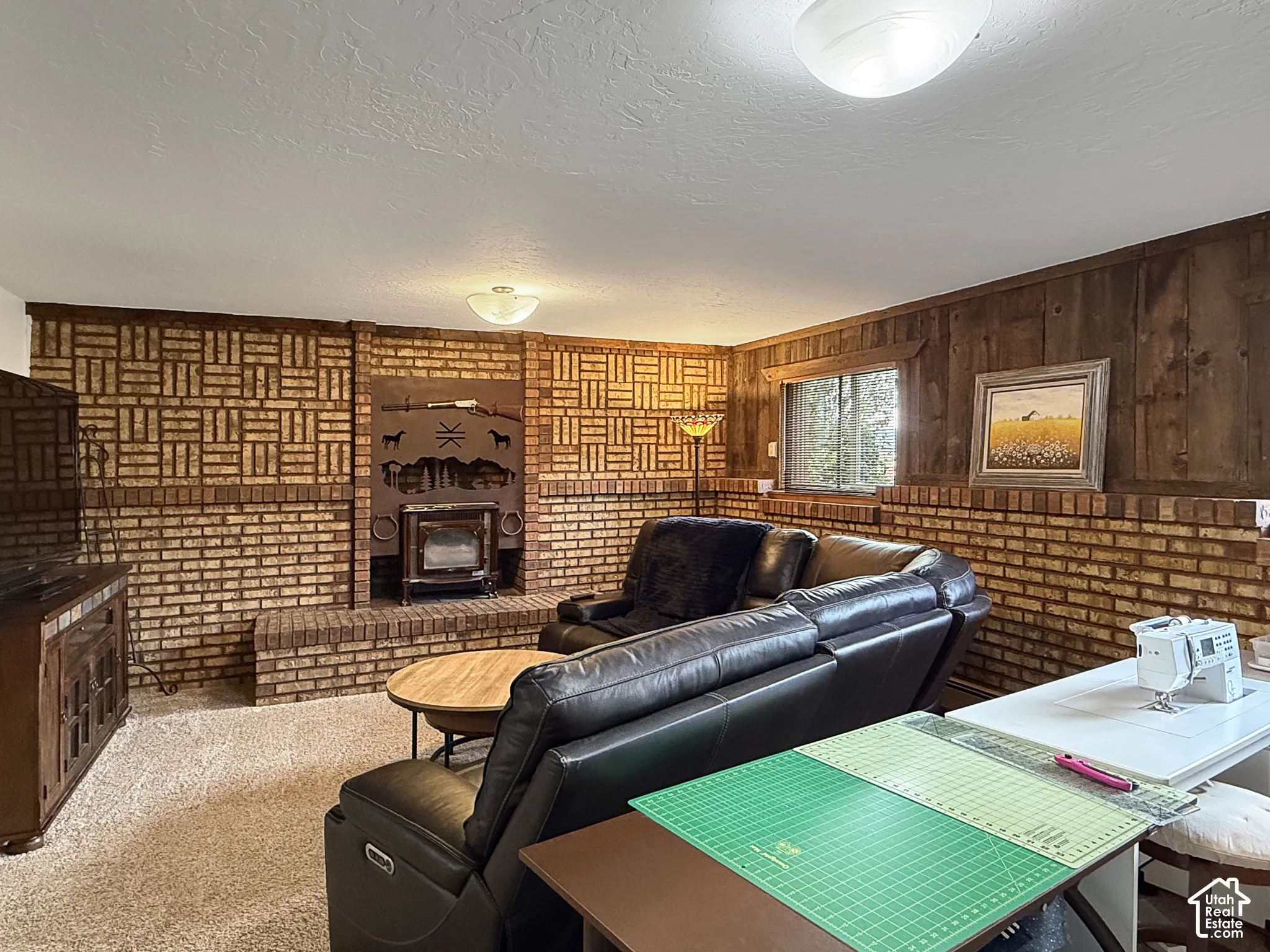 Brick fireplace with integrated wood-burning stove, textured brick wall detailing, and wood paneling