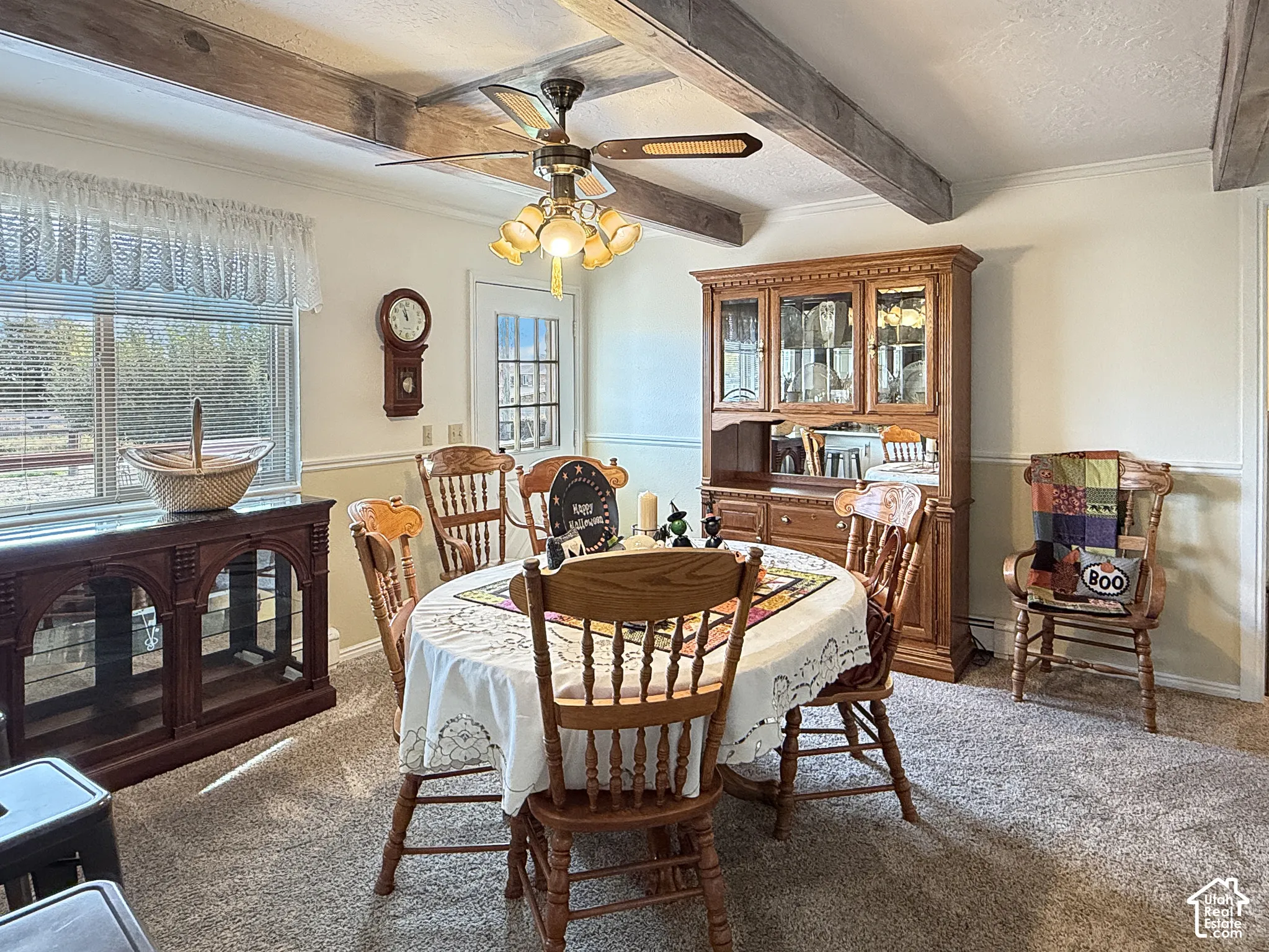 Dining area featuring exposed wooden ceiling beams, wainscoting, and a multi-light ceiling fan