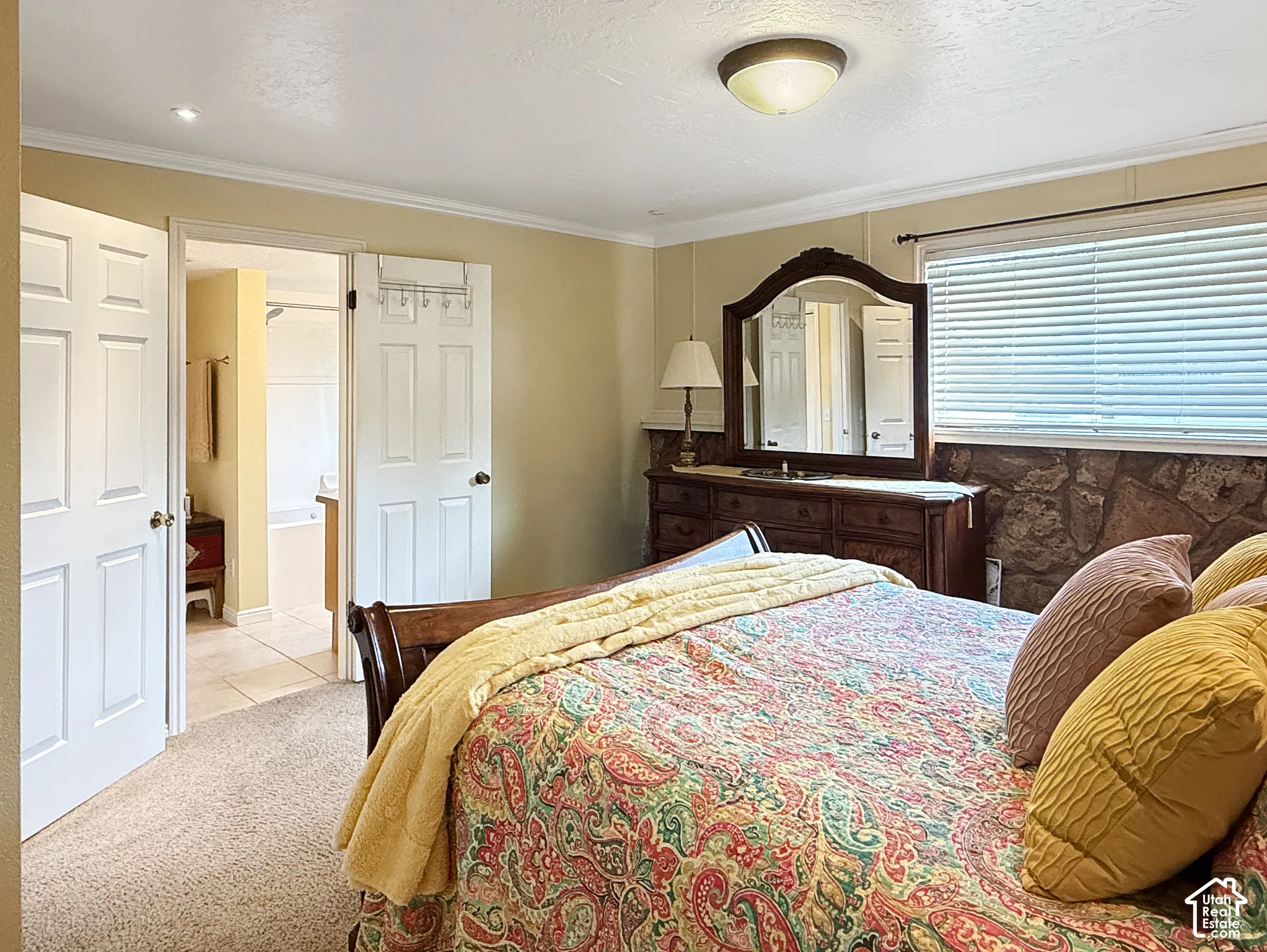Stone accent wall, window with horizontal blinds, neutral carpeting, and multi-panel interior doors
