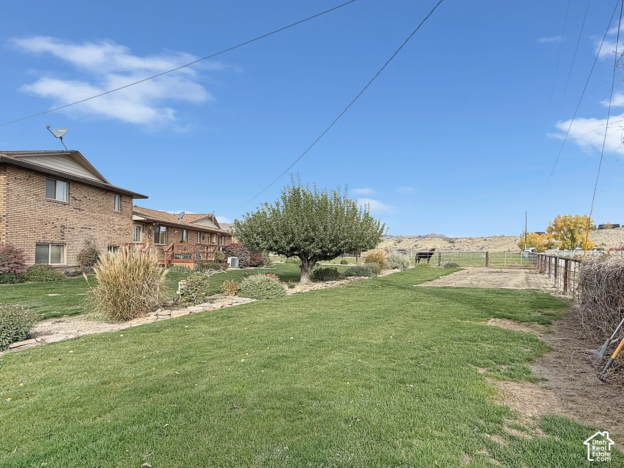 Expansive backyard featuring a brick exterior residence, mature landscaping, stone garden edging, and metal perimeter fencing