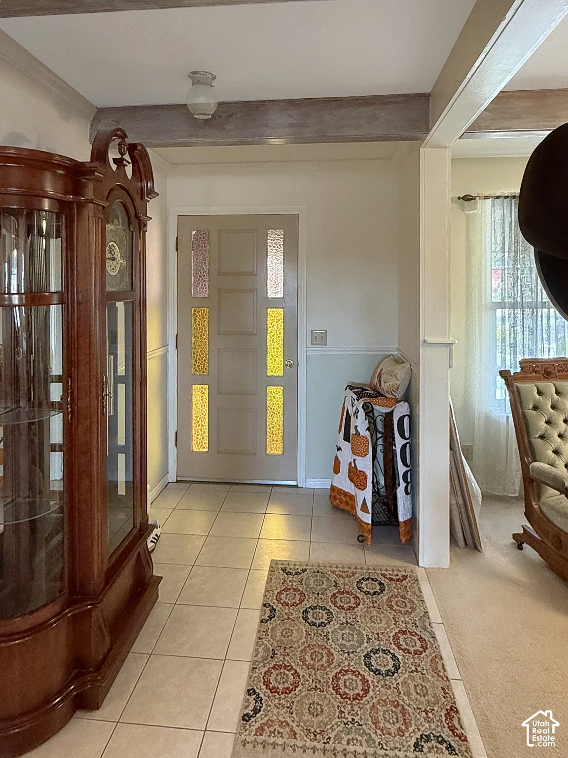 Entryway featuring tile flooring, exposed wooden ceiling beams, wainscoting, and a door with multi-pane textured glass inserts