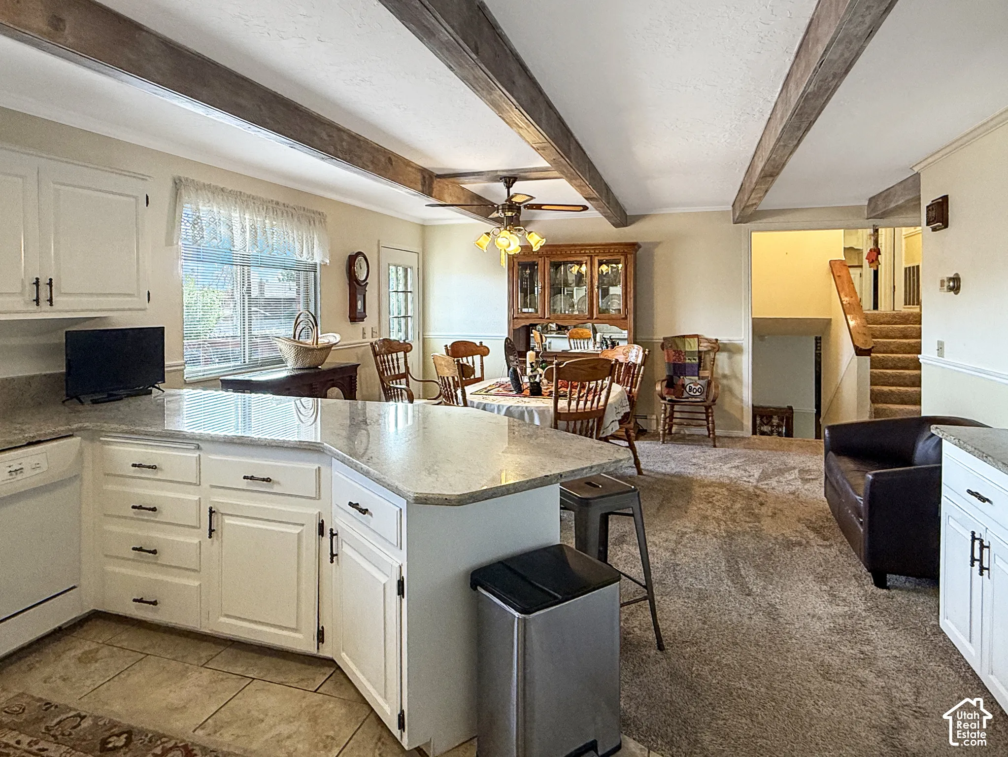 Kitchen featuring white cabinetry, stone-finish countertops, exposed ceiling beams, and tile flooring