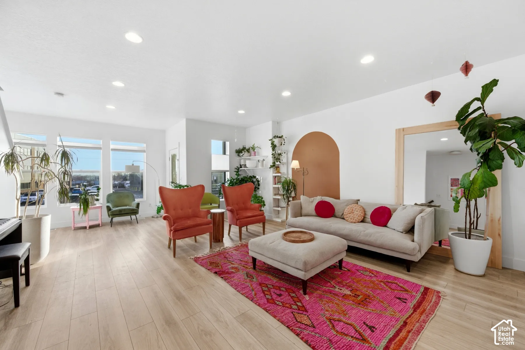 Open-concept room featuring recessed lighting, wood-finish flooring, large multi-pane windows, and an integrated arched wall detail