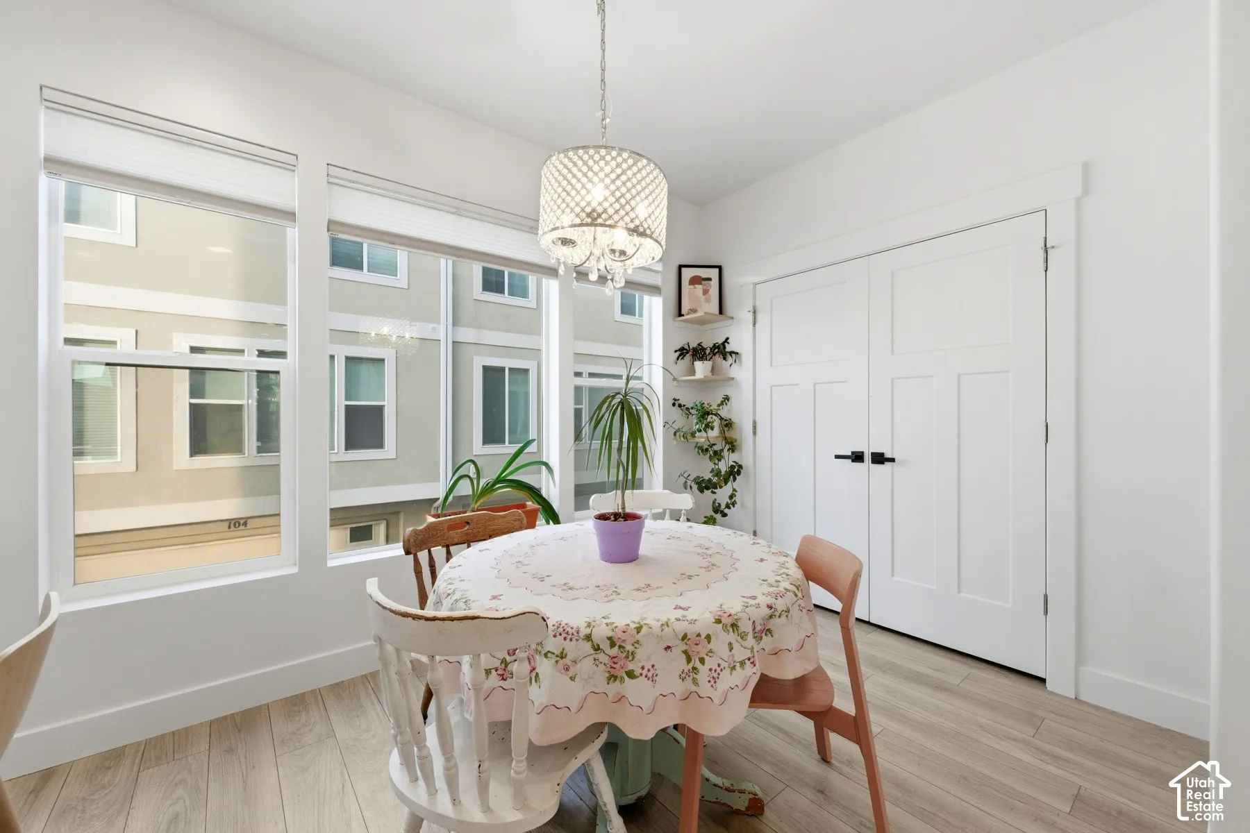 Room featuring wood-finish flooring, white double doors with matte black hardware, large windows, and a decorative drum-style chandelier