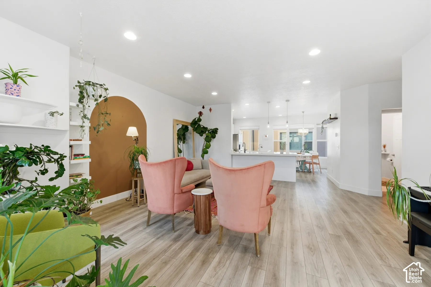Open-concept interior featuring wood-finish flooring, recessed lighting, built-in wall shelving, and a kitchen island with pendant lighting
