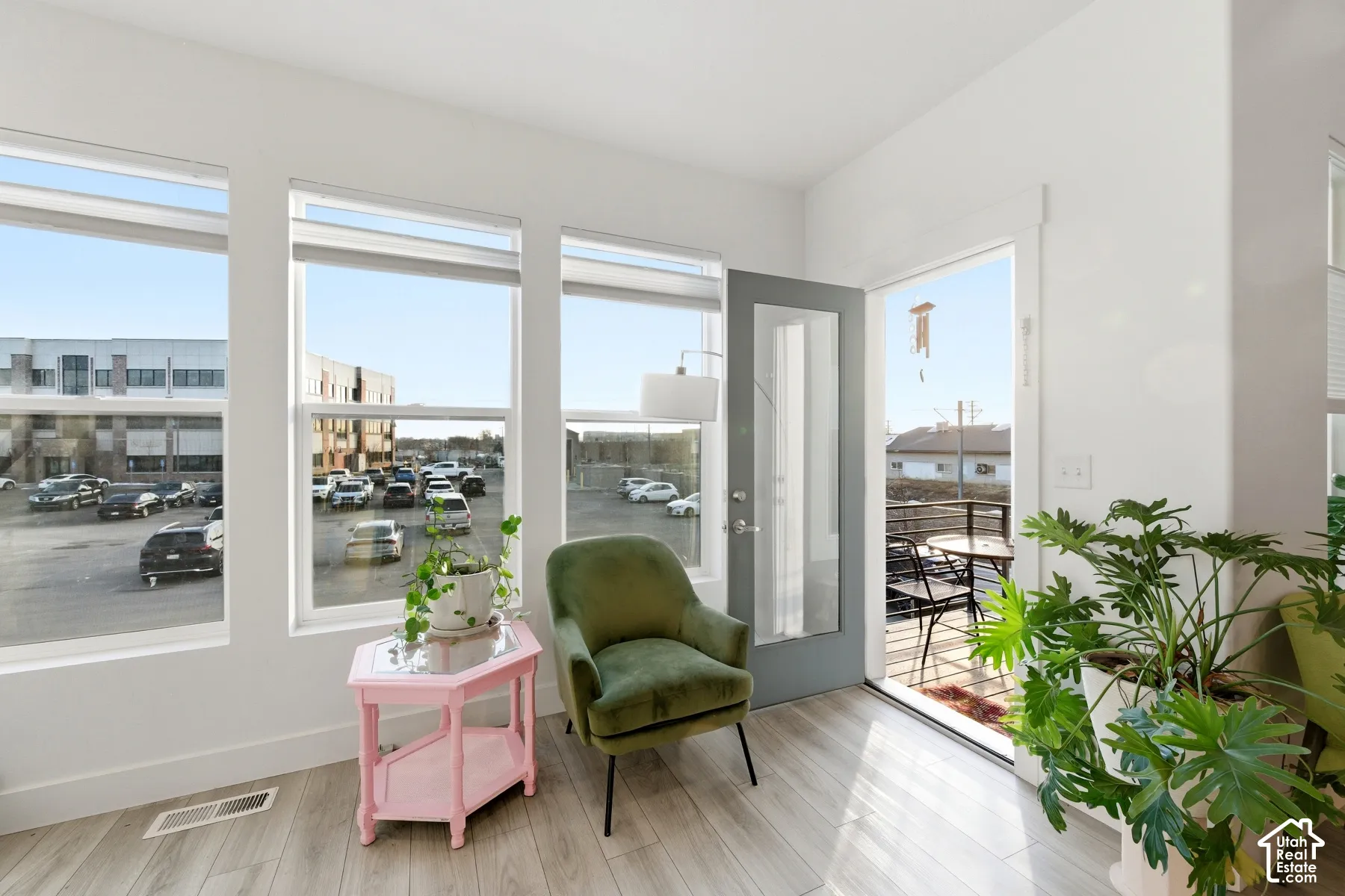 Full-height windows, wood-finish flooring, and a glass-paneled entry door providing access to an exterior balcony