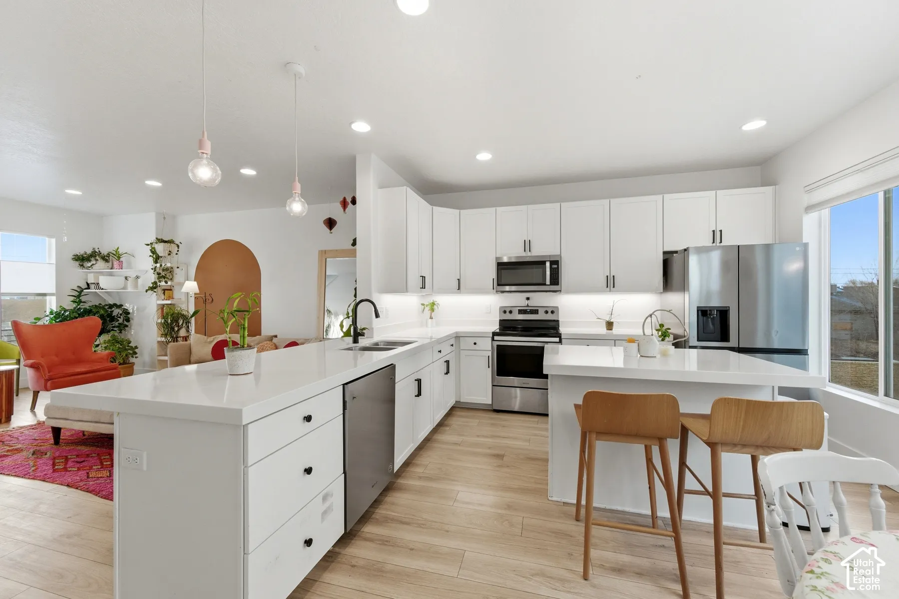 Kitchen featuring white cabinetry, quartz countertops, wood-finish flooring, stainless steel appliances, and pendant lighting