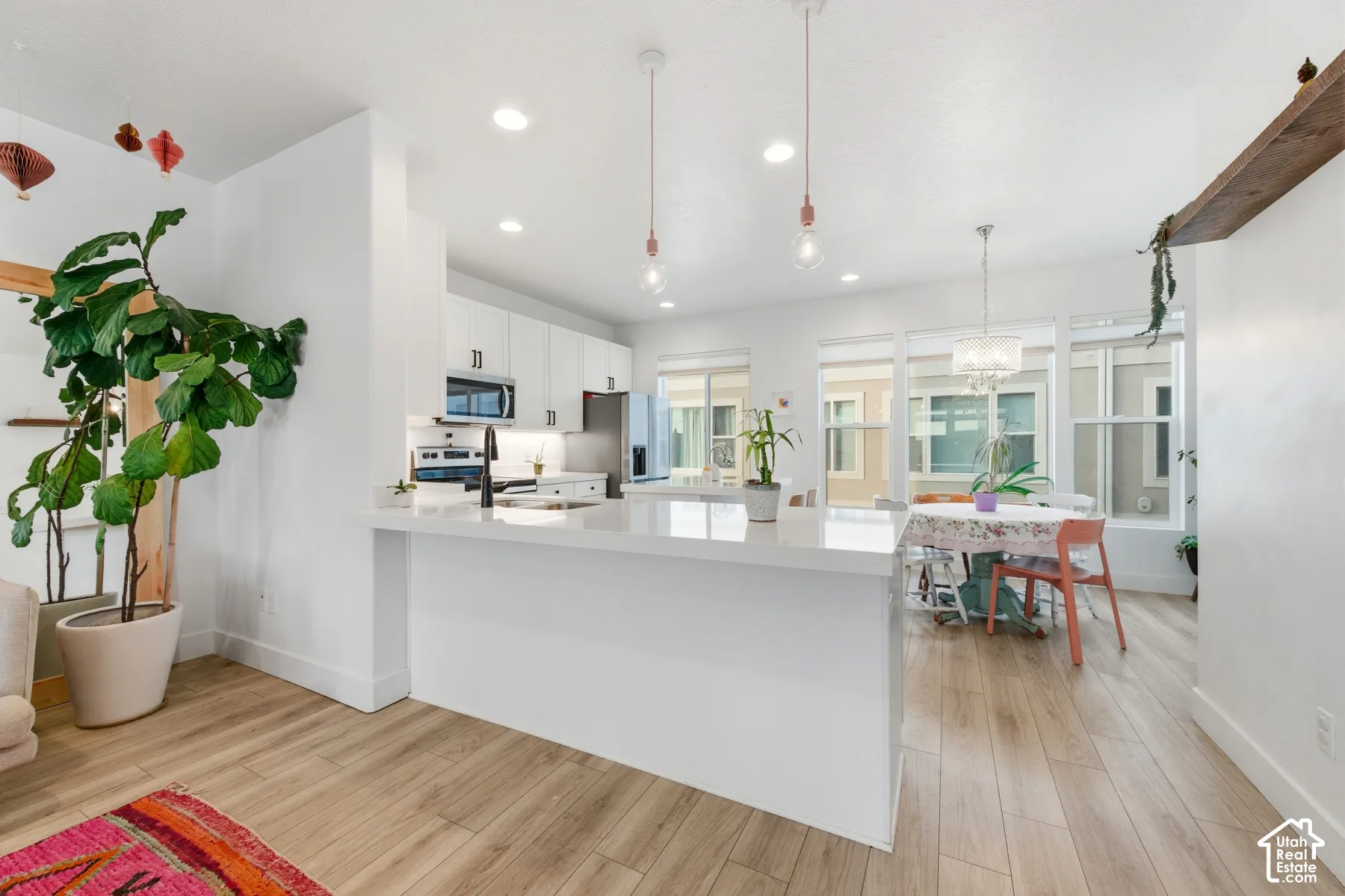 Kitchen featuring white cabinetry, quartz countertops, a peninsula with a faucet, recessed lighting, and wood-finish flooring
