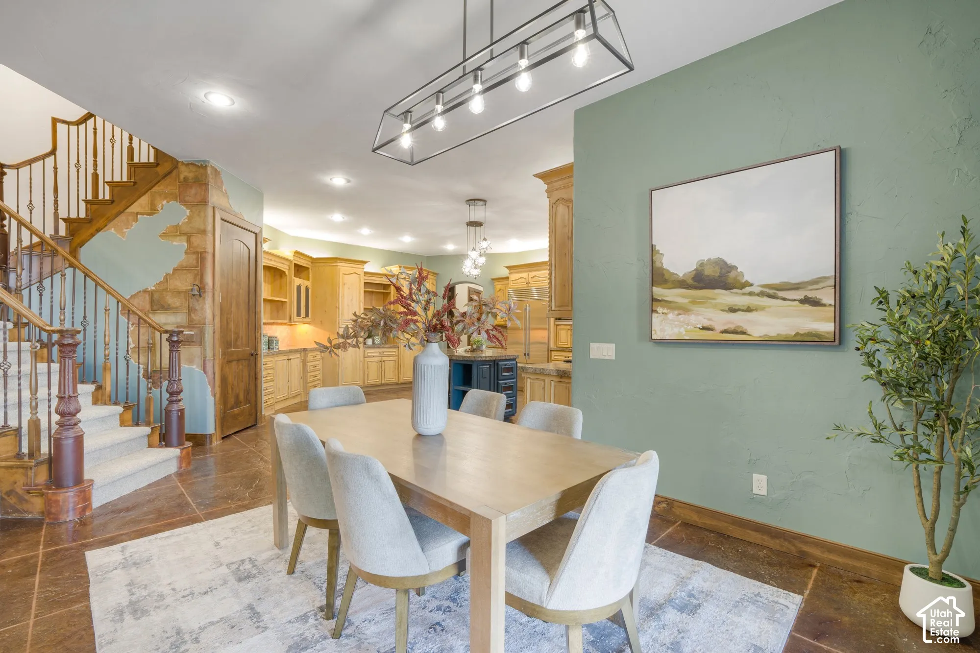 Open-concept area featuring stone accent wall detailing, wood-finish staircase with metal balusters, large-format tile flooring, and custom wood cabinetry