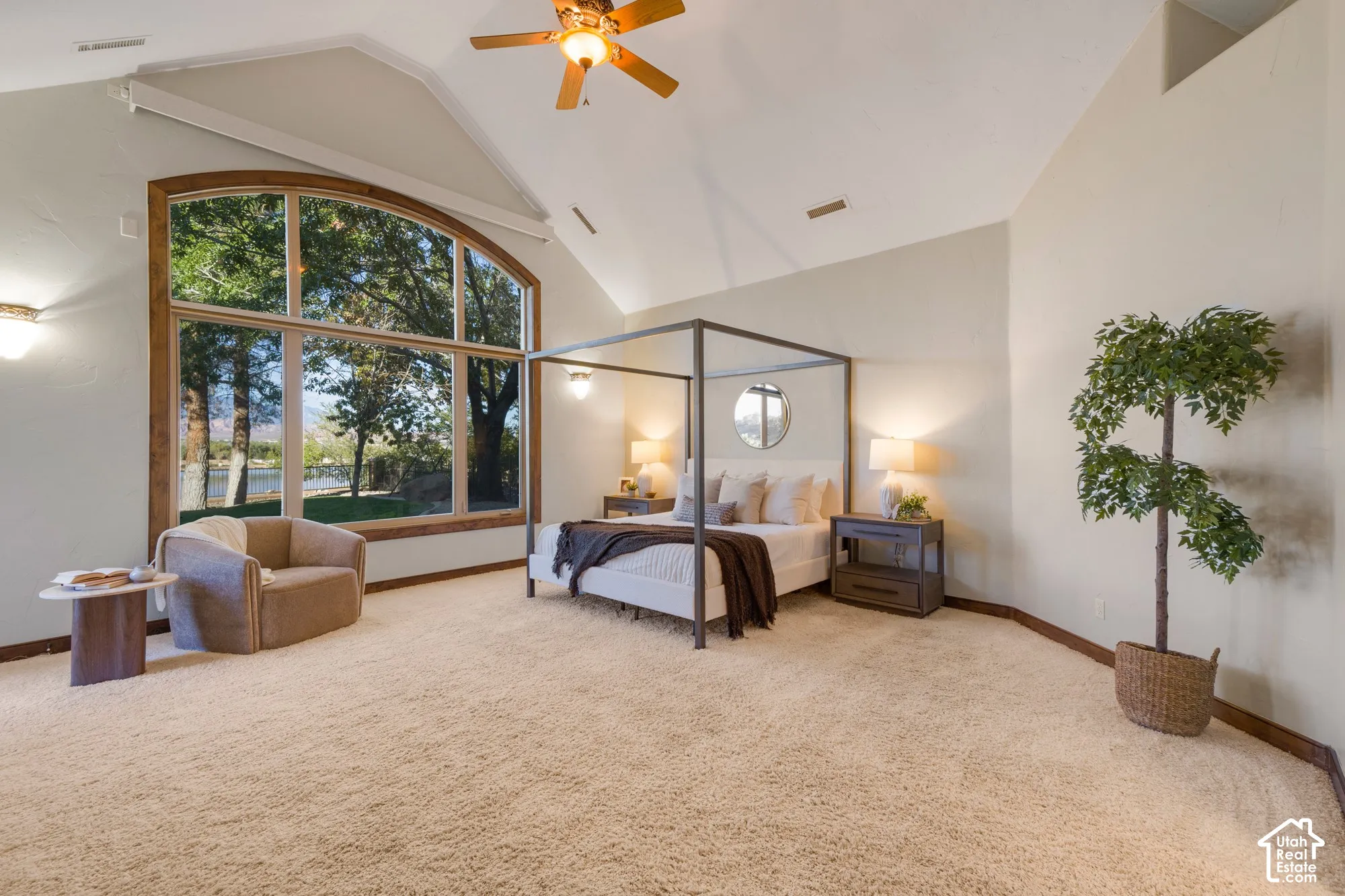 Vaulted ceilings, expansive arched window with wood trim, ceiling fan, and wall-mounted light fixtures