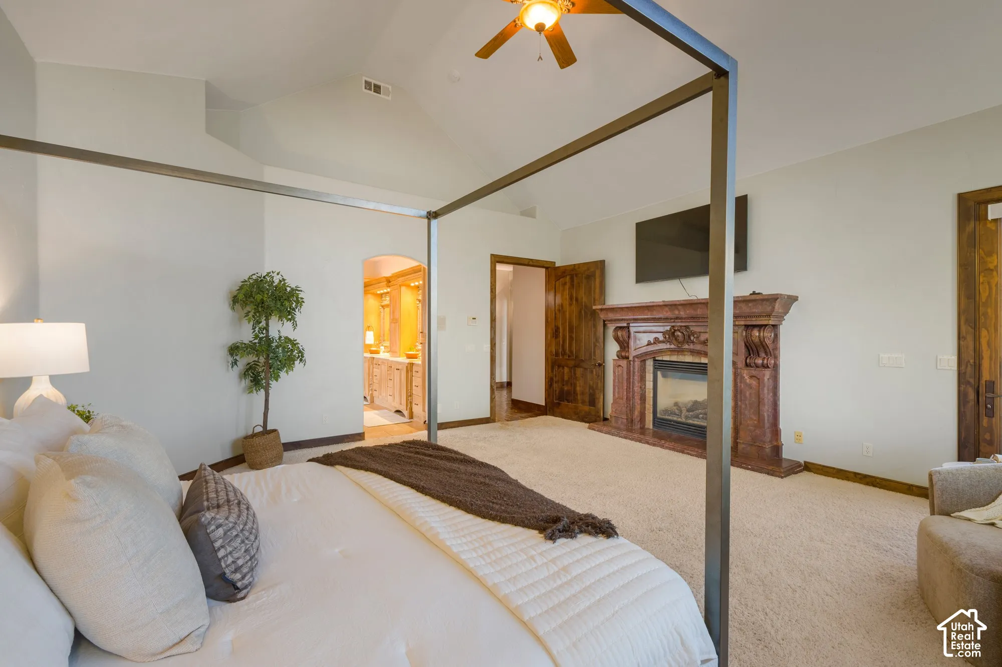 Vaulted ceilings featuring a central ceiling fan, fireplace with an ornate stone mantel, and solid wood interior doors