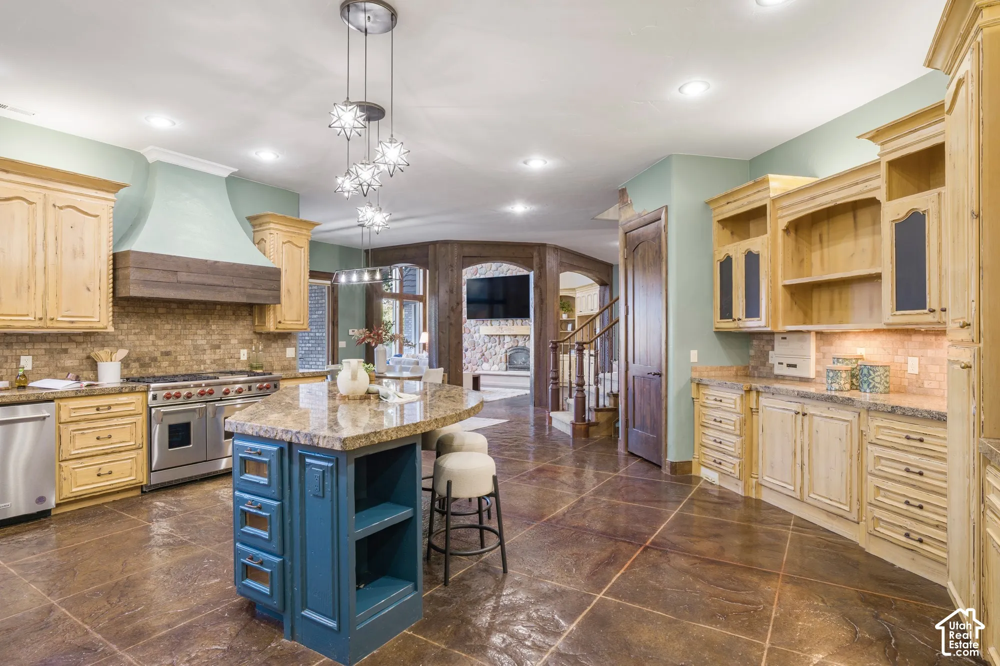 Kitchen featuring custom wood cabinetry, stone-finish countertops, stainless steel professional-grade range, tiled backsplash, and stone-finish flooring