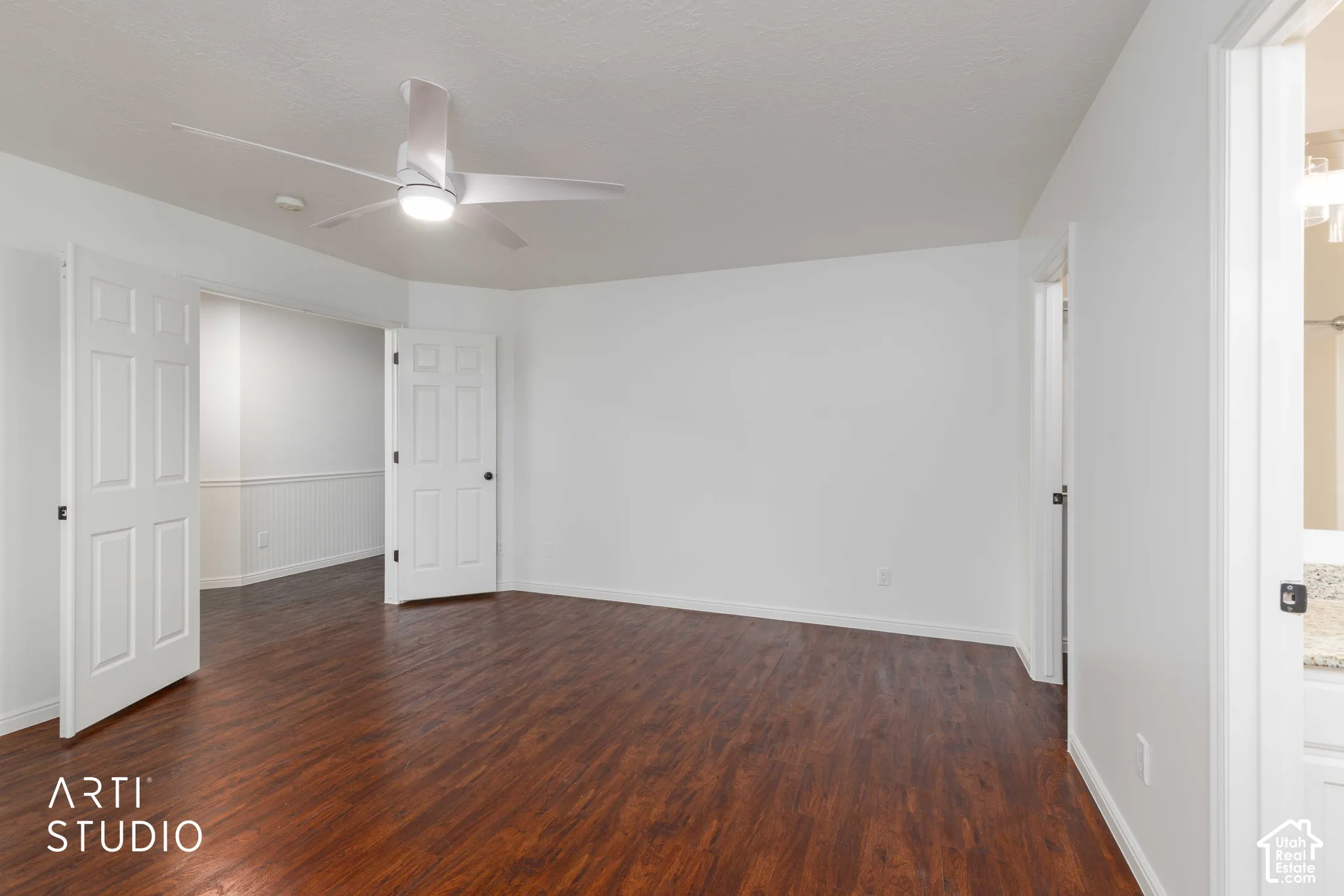 Wood-finish flooring, white paneled interior doors, and a ceiling-mounted light fixture with integrated fan