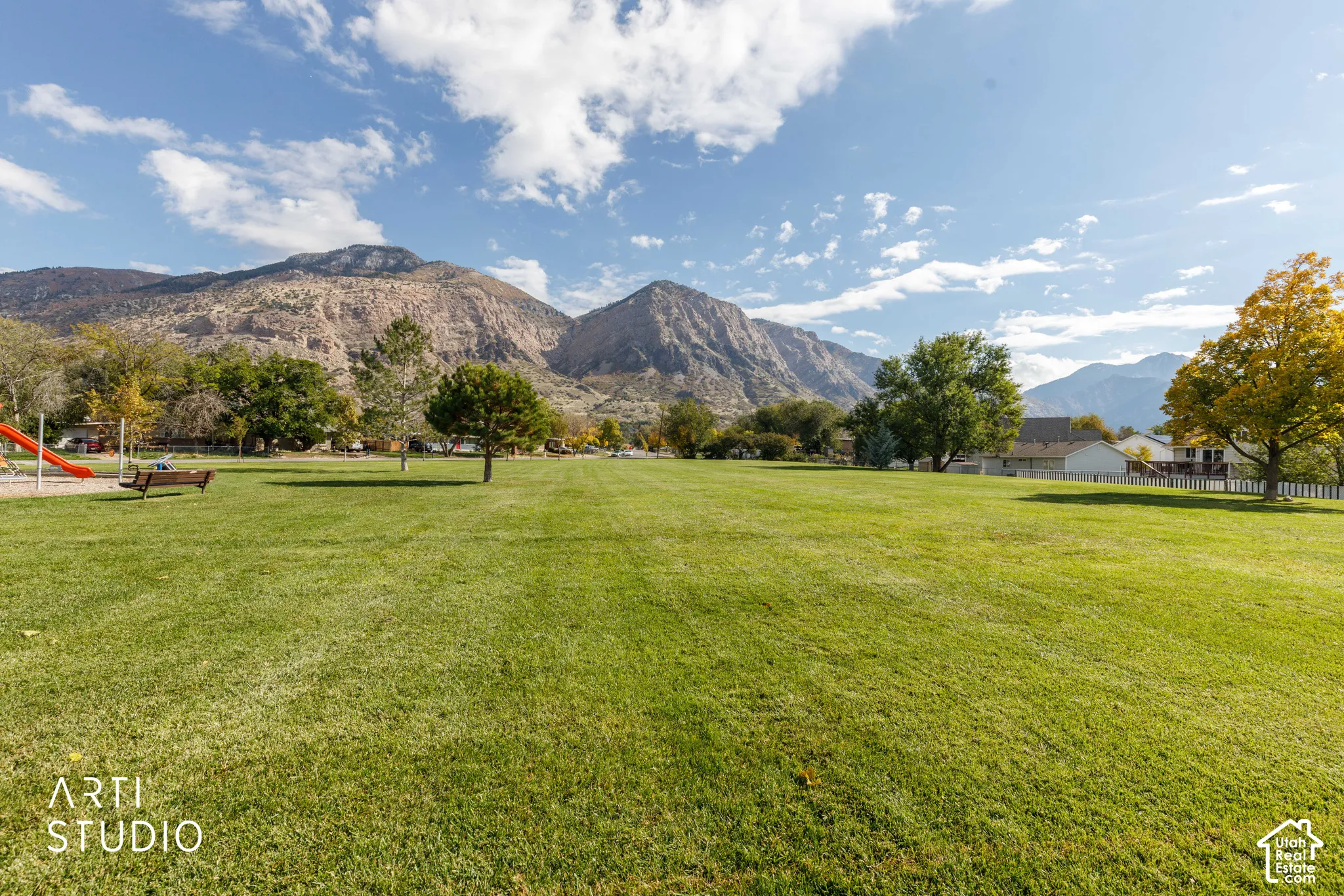 Expansive manicured lawn featuring mature trees and a mountain backdrop
