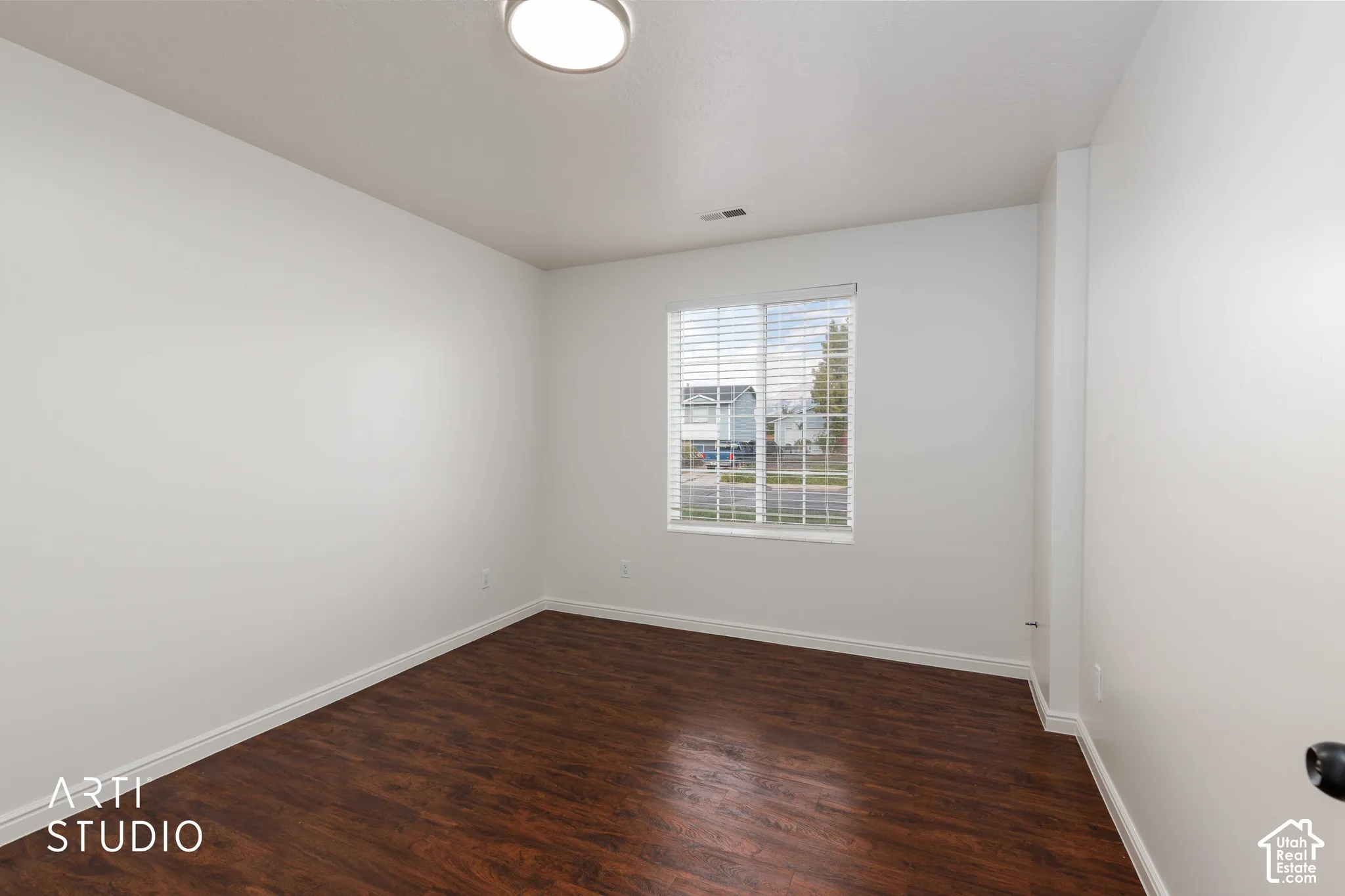 Room featuring dark wood-finish flooring, white walls, a single-pane sliding window, and a flush-mount overhead light fixture