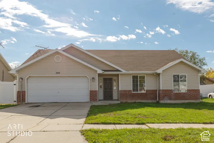 Single-story residence featuring light-toned vinyl siding, brick masonry accents, an attached two-car garage, and a concrete driveway