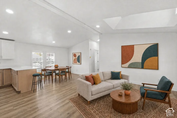 Open-concept interior featuring vaulted ceilings, a skylight, recessed lighting, and wood-finish flooring