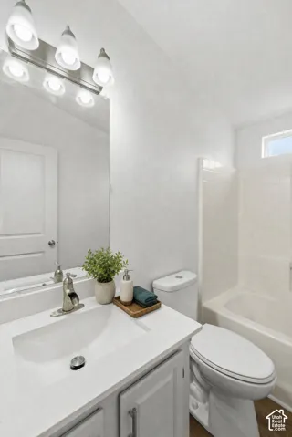 Bathroom featuring a white vanity with a rectangular sink, brushed nickel faucet, large wall-mounted mirror, multi-bulb light fixture, and a white tile tub-shower combination