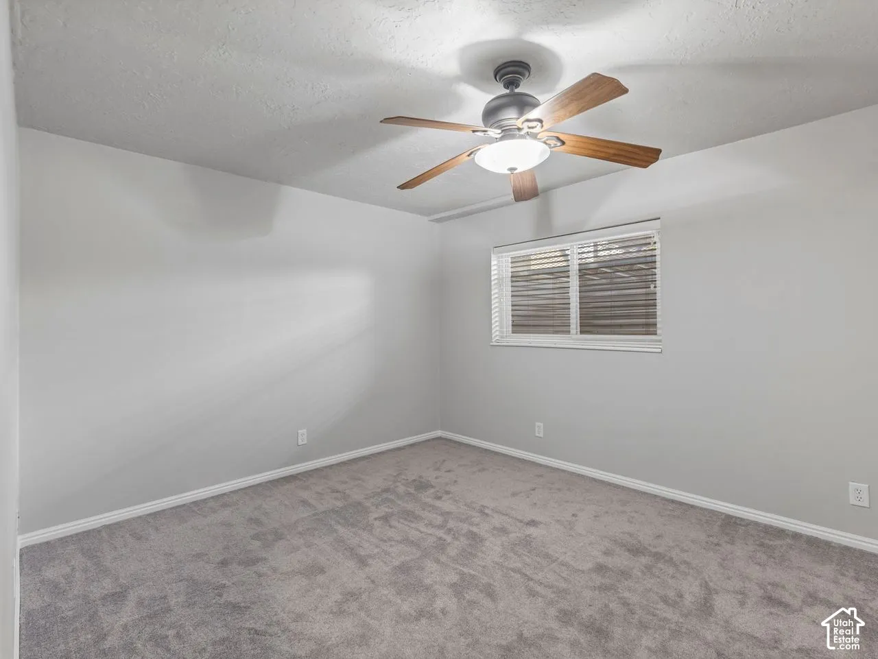 Neutral wall finishes, plush carpeting, ceiling fan with integrated lighting, and horizontal window blinds