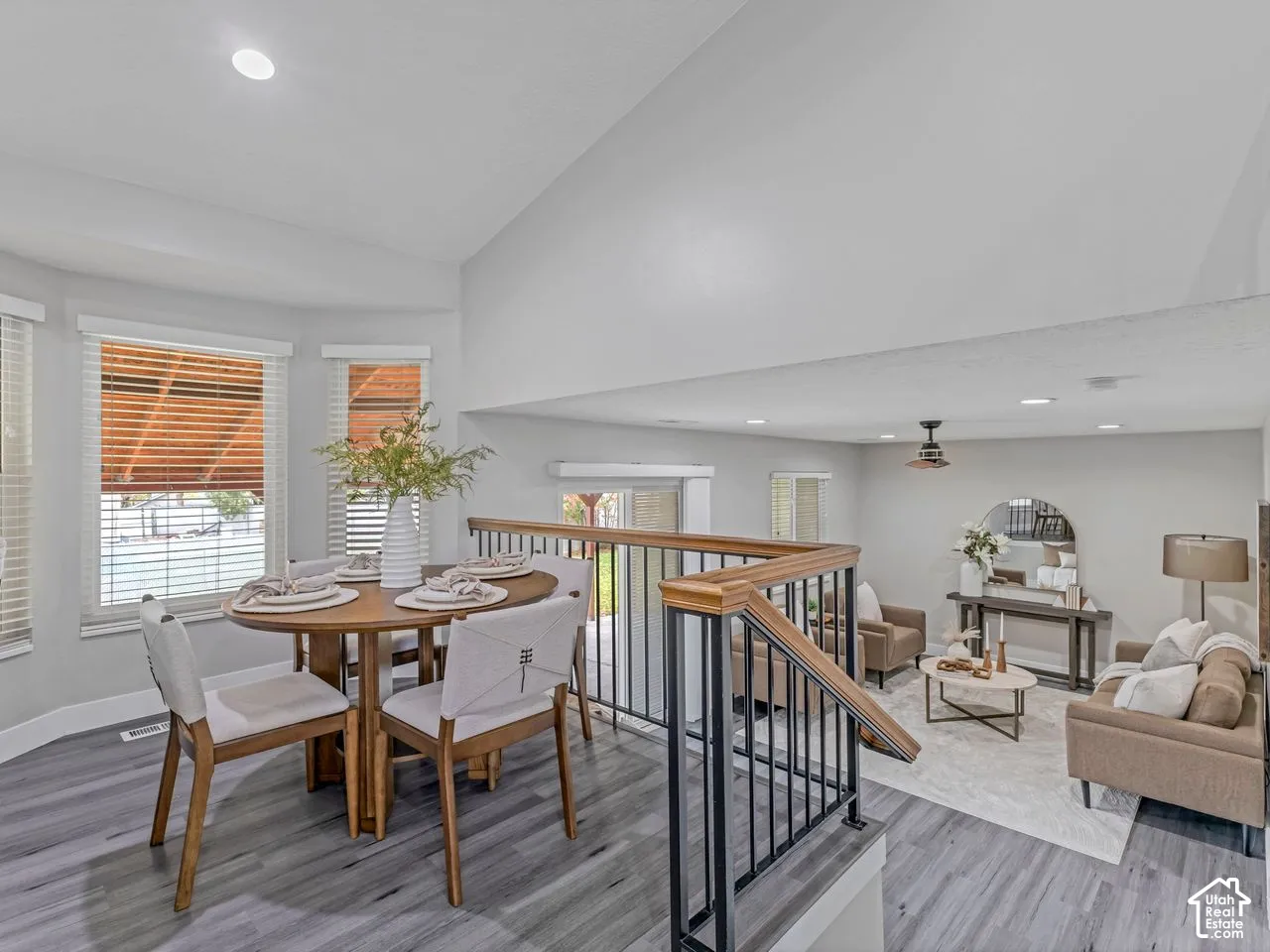Vaulted ceiling, wood-finish flooring, recessed lighting, and metal staircase railing with a wood-finish handrail